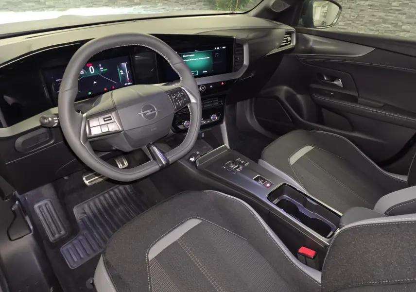 Vue intérieure avant droite de l’Opel Mokka-e 2025 gris, avec volant multifonction et écran tactile 10 pouces.