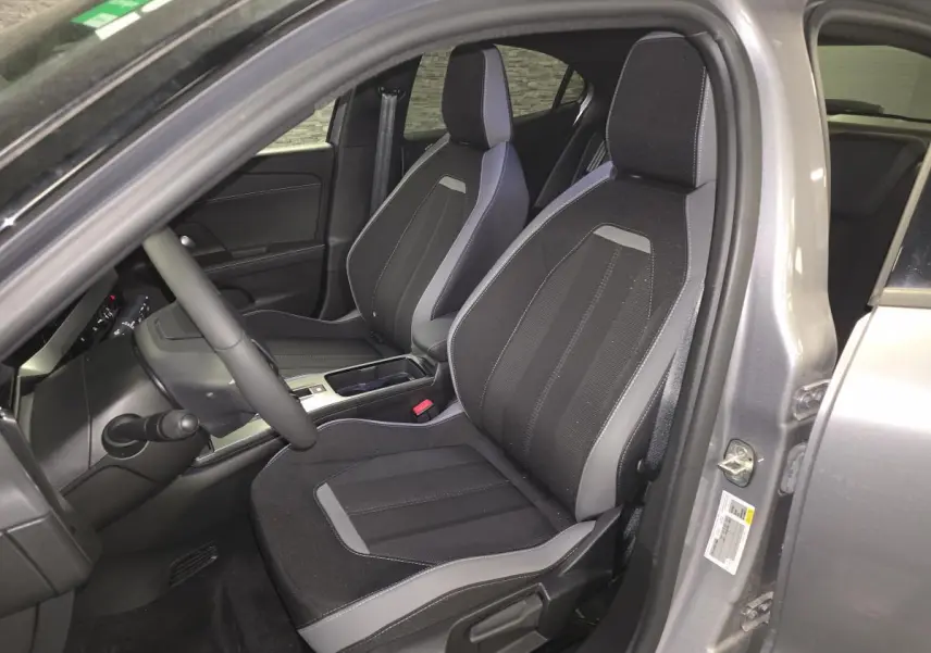 Vue intérieure côté conducteur de l'Opel Mokka-e gris 2025, sièges tissu noir et gris avec console centrale visible.