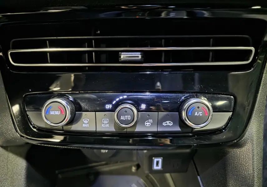 Détail de la console centrale noire avec commandes de climatisation automatique et ventilation du Opel Mokka-e gris.