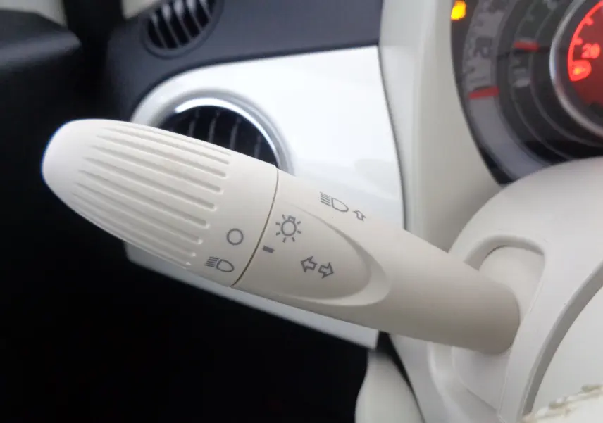Gros plan sur la commande d'éclairage beige à gauche du volant d'une FIAT 500 blanc gelato 2023.