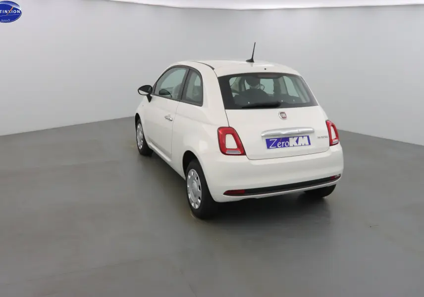 Fiat 500 blanc gelato vue 3/4 arrière droit dans un studio, avec badge hybride et plaque Zero KM.