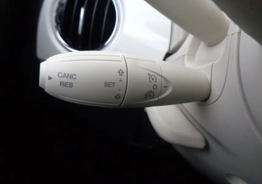 Gros plan sur la commande de régulateur de vitesse blanc cassé dans l'habitacle d'une FIAT 500 blanc gelato 2023.