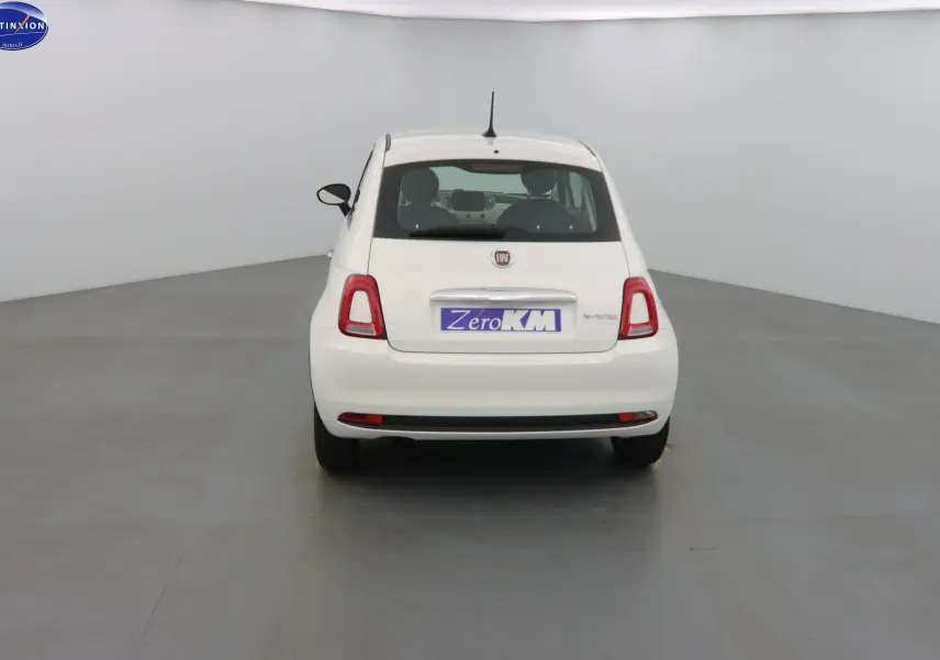 Vue arrière d'une FIAT 500 blanc gelato hybride 2023 avec feux arrière rouges et plaque Zero KM.