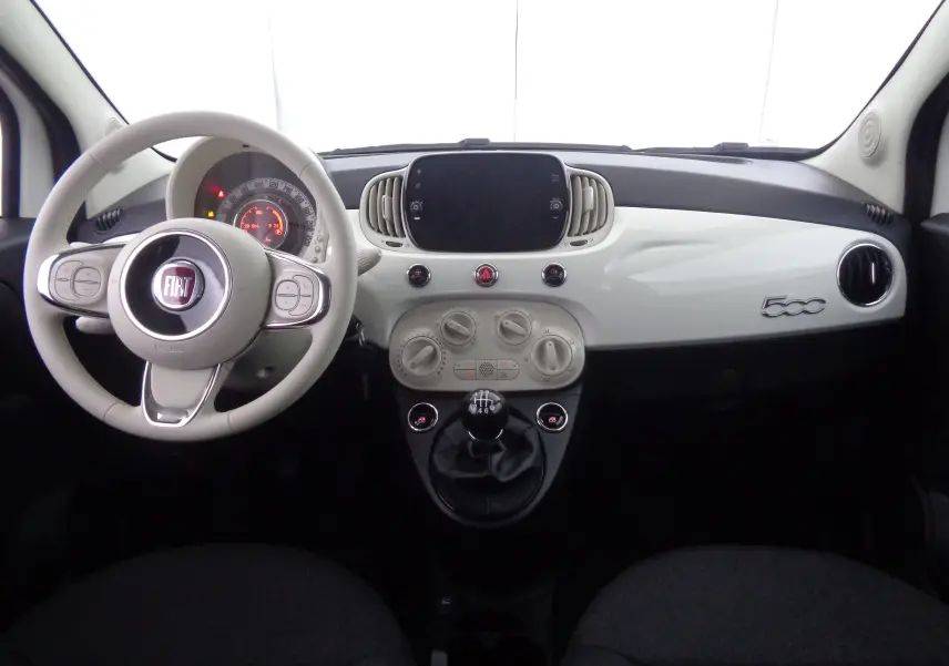 Vue frontale de l'habitacle blanc gelato de la Fiat 500 1.0 Hybrid 2023 avec tableau de bord épuré et volant rond.