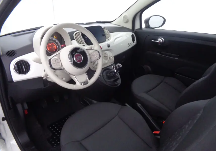 Intérieur de la Fiat 500 2023 en blanc gelato, vue côté conducteur montrant tableau de bord et volant clair.