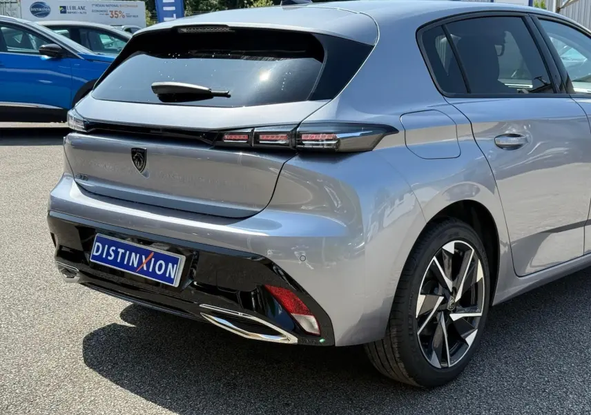 Peugeot 308 gris Artense vue 3/4 avant droit, avec jantes alliage et calandre noire distinctive.