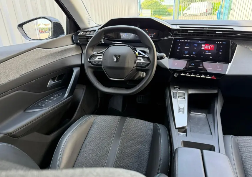Vue intérieure avant de la Peugeot 308 2024, tableau de bord moderne avec écran tactile et volant compact noir.