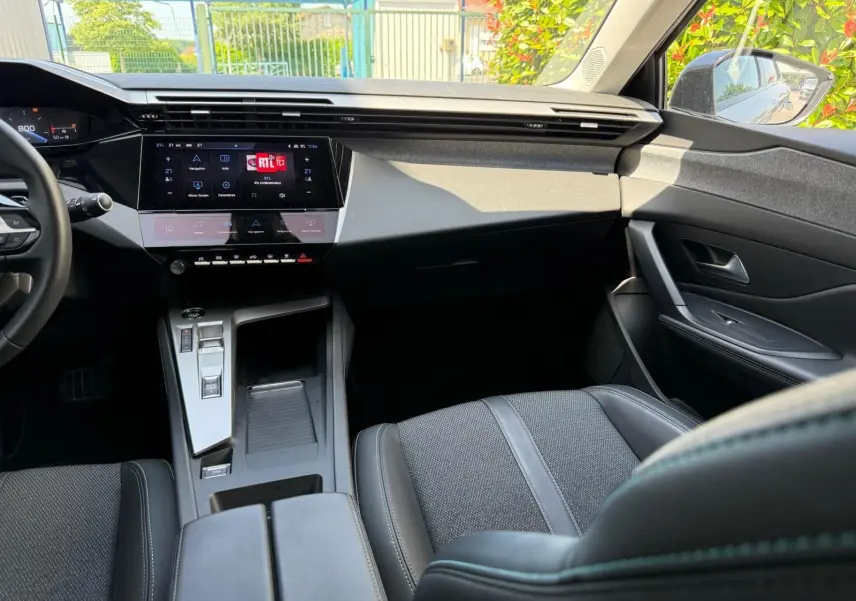 Intérieur avant droit de la Peugeot 308 2024 gris Artense, avec tableau de bord numérique et console centrale moderne.