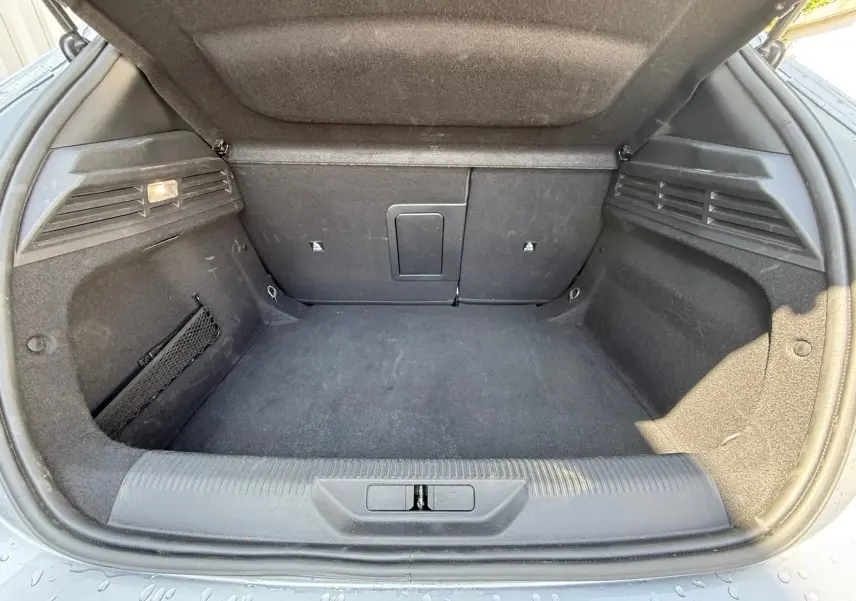 Coffre ouvert d'une Peugeot 308 gris Artense, montrant un espace de chargement propre et bien agencé.