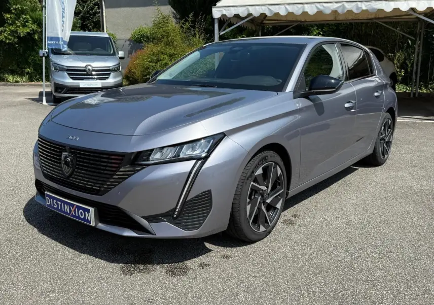 Peugeot 308 gris Artense vue 3/4 avant droit, mettant en valeur sa calandre noire et ses phares LED fins.