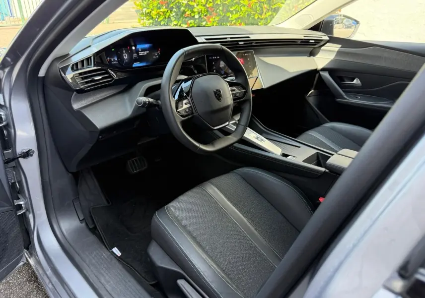 Intérieur avant droit de la Peugeot 308 gris Artense 2024, tableau de bord numérique et volant compact multifonction.