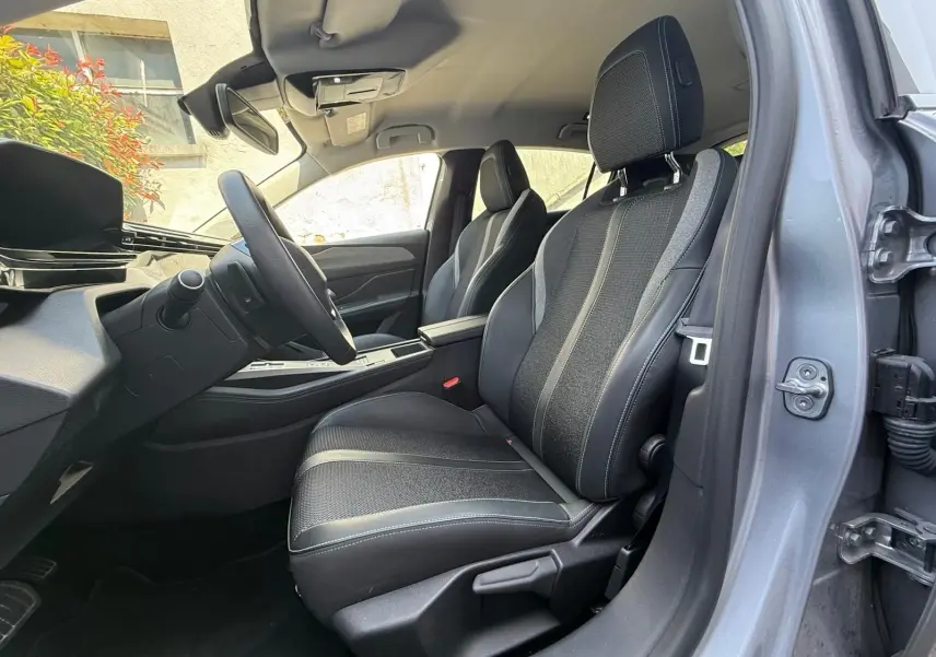 Intérieur avant droit de la Peugeot 308 2024 gris Artense, sièges tissu et cuir avec surpiqûres contrastées.