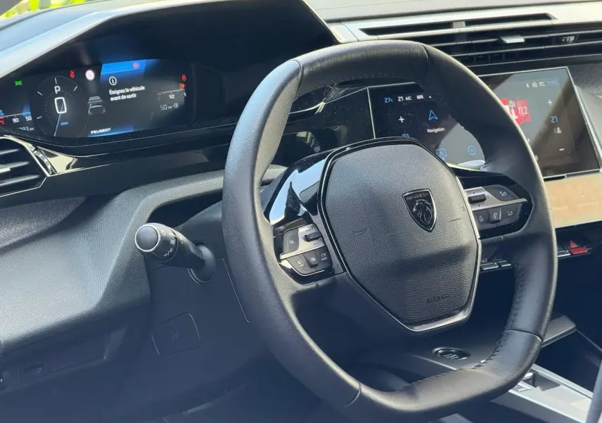 Vue rapprochée du volant cuir noir et du tableau de bord numérique de la Peugeot 308 gris Artense 2024.