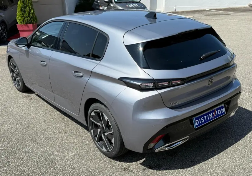 Vue 3/4 arrière droite d'une Peugeot 308 gris Artense 2024 avec feux LED et jantes alliage distinctives.