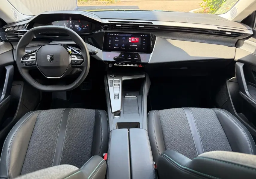 Intérieur de la Peugeot 308 2024 en gris, vue frontale du tableau de bord avec écran tactile et volant multifonction.