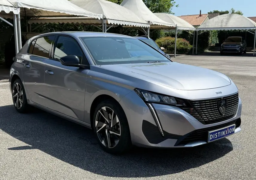 Vue 3/4 avant droit de la Peugeot 308 gris Artense avec calandre noire et jantes alliage distinctives.