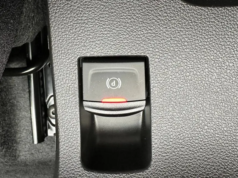 Gros plan sur le bouton de frein de stationnement électrique avec témoin rouge du Dacia Jogger noir nacré.