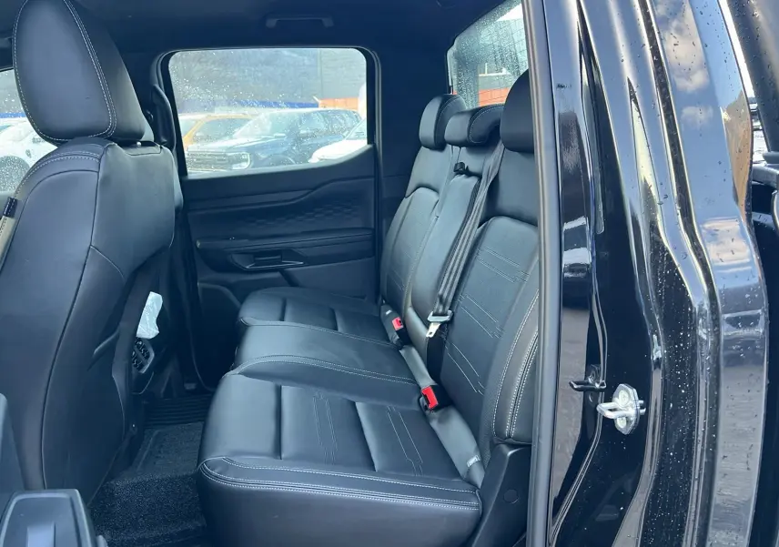 Vue côté droit des sièges arrière en cuir noir du Ford Ranger 2025 Noir Shadow avec portière ouverte.