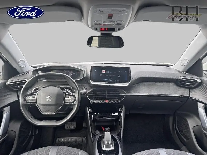 Vue intérieure frontale du tableau de bord du Peugeot 2008 blanc banquise avec volant compact et écran tactile central.