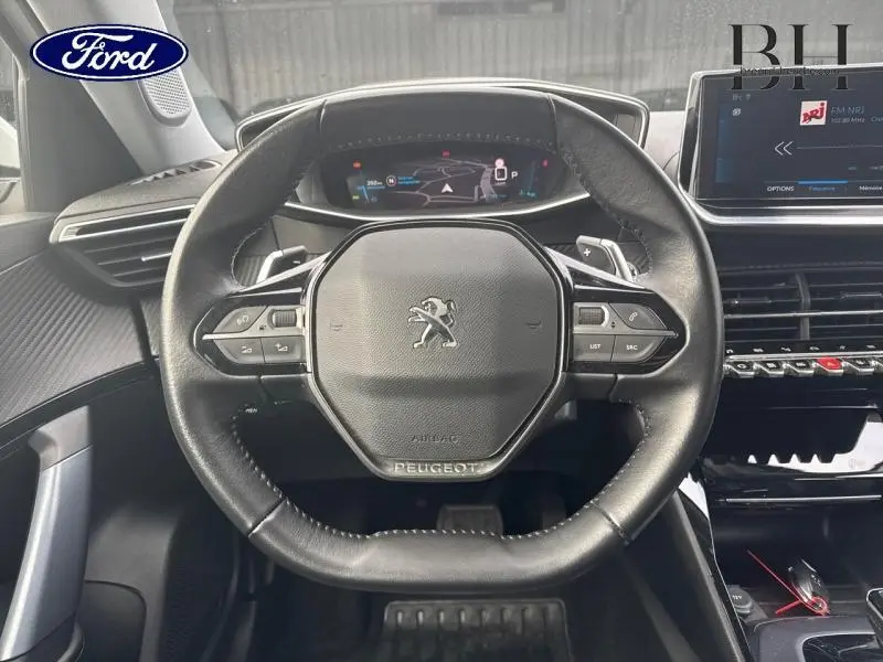 Vue rapprochée du volant Peugeot 2008 noir avec tableau de bord numérique et écran central tactile.