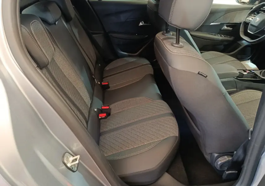 Vue intérieure côté gauche montrant la banquette arrière gris clair et les sièges avant de la Peugeot 208 PureTech 100 S&S Allure 2025.