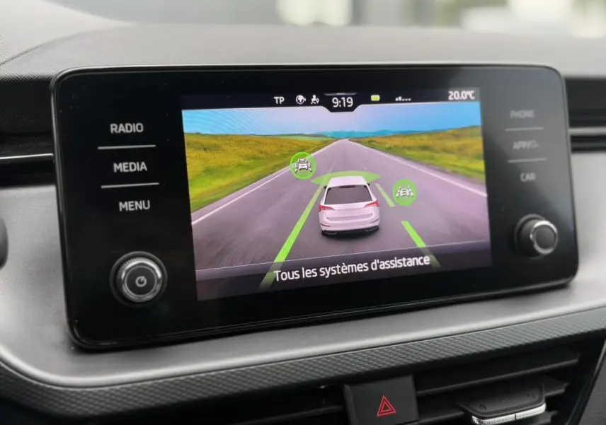 Écran tactile central de la Skoda Scala TSI 110 DSG Ambition montrant l'assistance à la conduite sur fond de route.