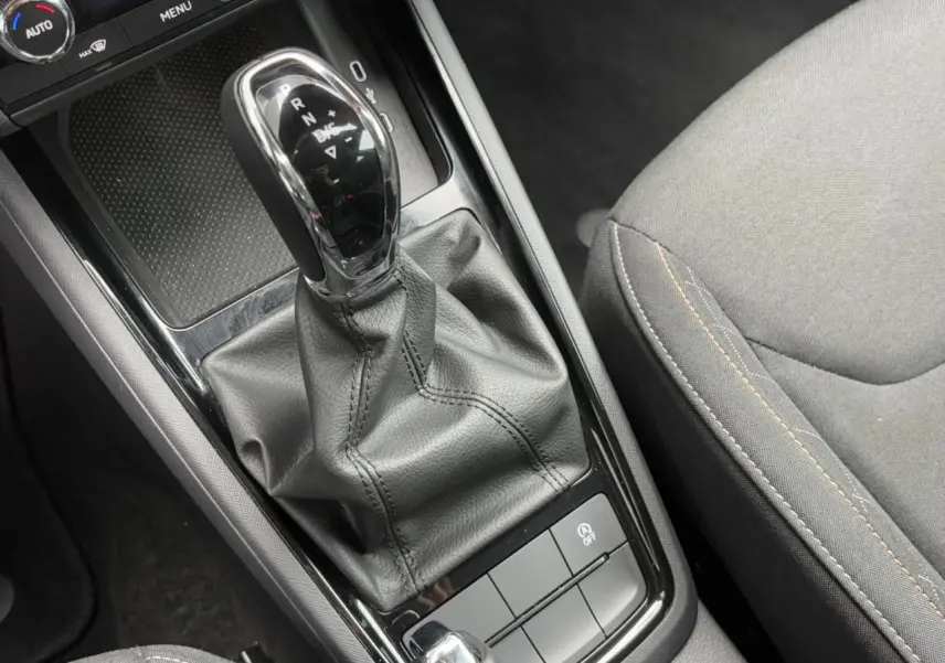 Le levier de vitesse automatique noir et chrome de la Skoda Scala TSI 110 DSG Ambition vu de dessus avec siège gris adjacent.