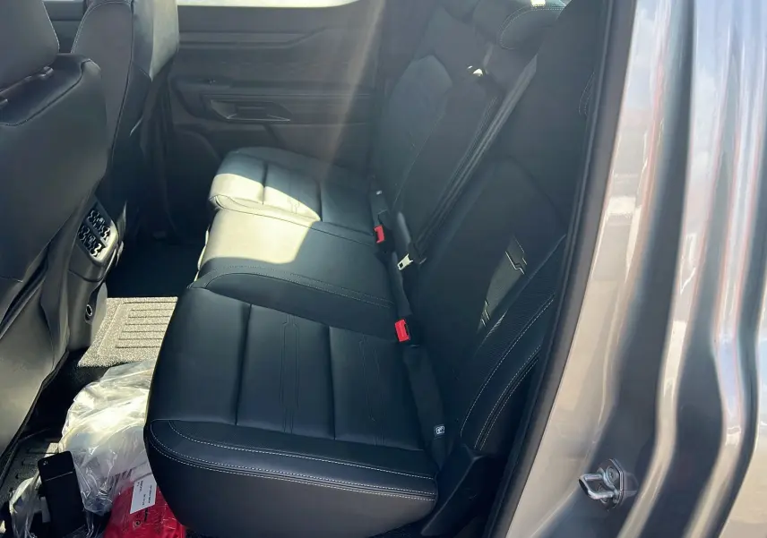 Vue intérieure côté droit des sièges arrière en cuir noir du Ford Ranger 2025 gris iconic, avec ceinture de sécurité rouge visible.