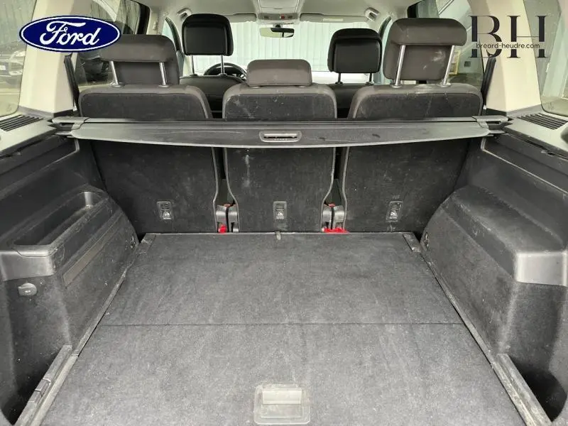 Coffre spacieux vu de l'arrière avec banquette arrière noire et cache-bagages dans un Volkswagen Touran noir nacré