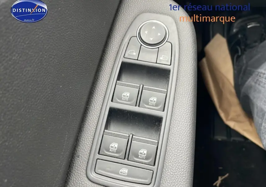 Gros plan sur les commandes des vitres électriques côté conducteur de la Renault Clio V blanche, avec réglage des rétroviseurs.