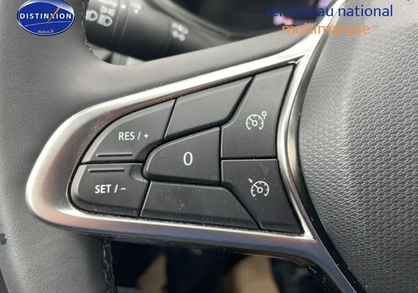 Gros plan sur les commandes du régulateur de vitesse au volant d’une Renault Clio V blanche, version 2025.