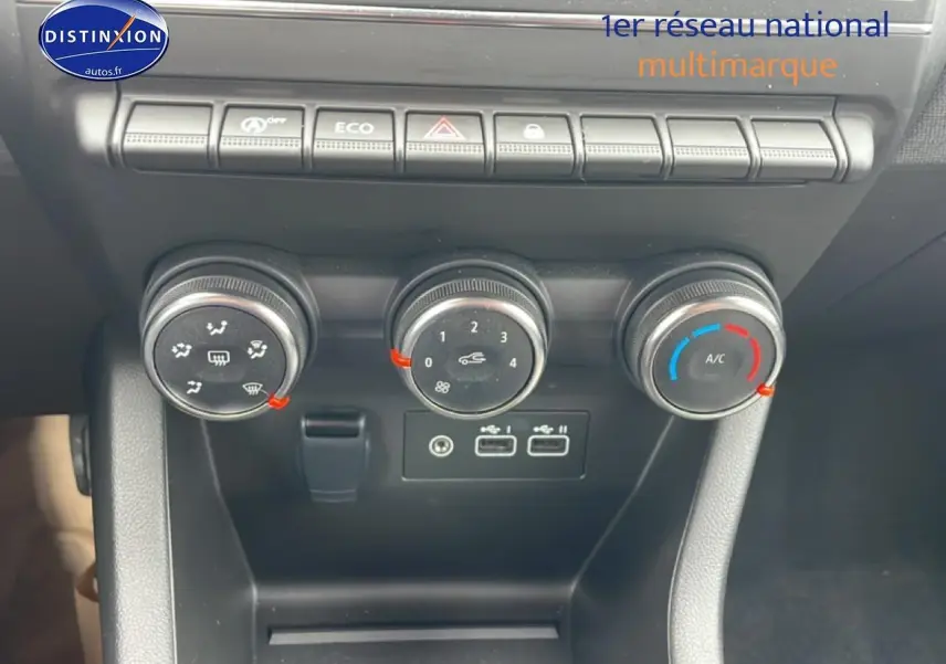 Vue rapprochée des commandes de climatisation et des ports USB d'une Renault Clio V blanche, tableau de bord noir.