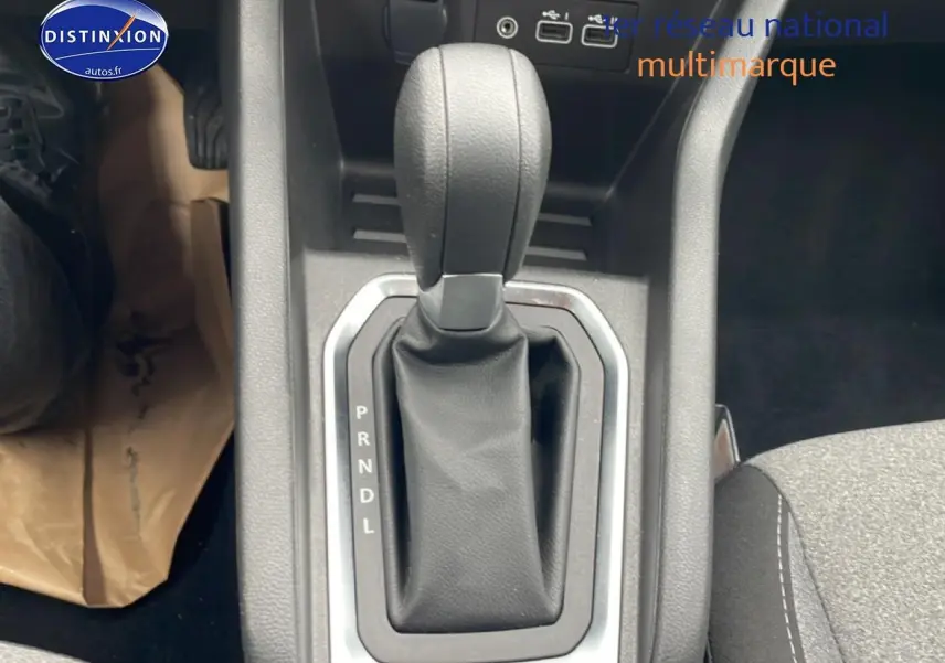 Le levier de vitesse automatique noir de la Renault Clio V 2025 vu de dessus avec console grise et siège tissu gris.