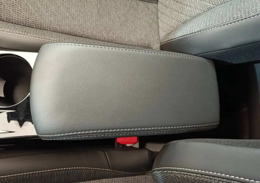 Vue rapprochée de l'accoudoir central gris foncé et des sièges tissu gris clair de la Peugeot 208 PureTech 100 S&S Allure.