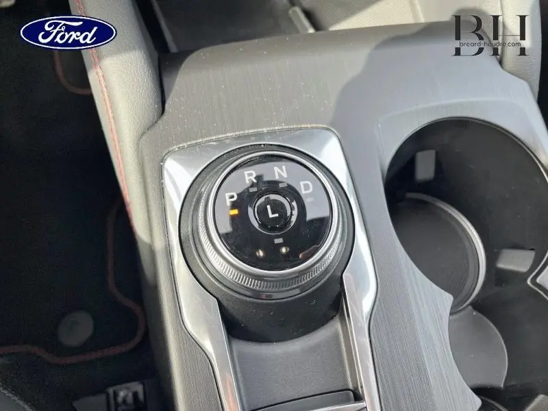 Gros plan sur la molette de sélection de la boîte automatique du Ford Kuga gris Solar, avec porte-gobelets à droite.