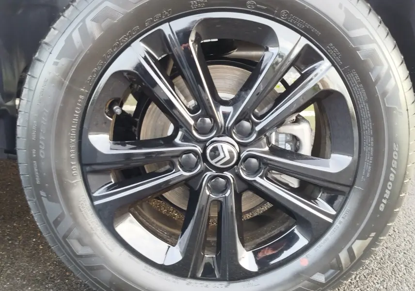 Gros plan sur la jante noire brillante avec logo Citroën d’un Citroën Berlingo Kaolin White, roue avant droite.