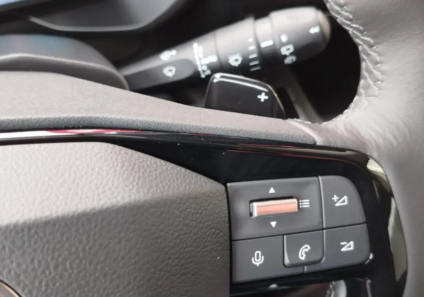 Gros plan sur les commandes au volant gris foncé du Citroën Berlingo 2025, avec molette et boutons multifonctions.