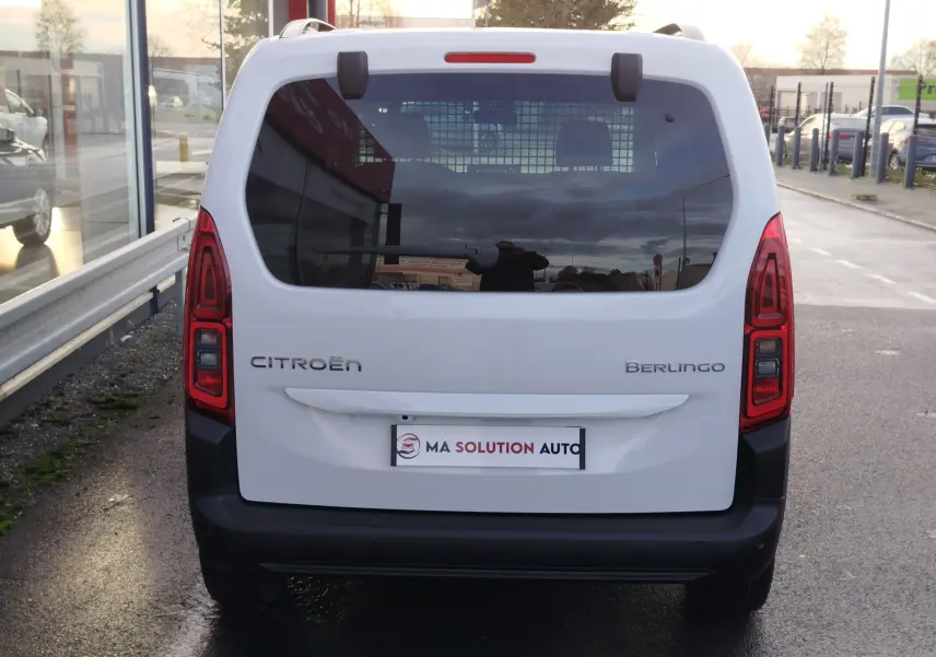 Vue arrière d'un Citroën Berlingo blanc Kaolin avec vitres teintées et feux arrière rouges allumés.