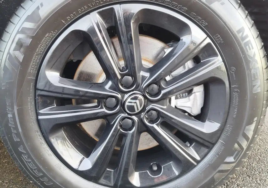 Gros plan sur la jante noire brillante avec logo Citroën au centre, montée sur pneu Nexen visible en extérieur.