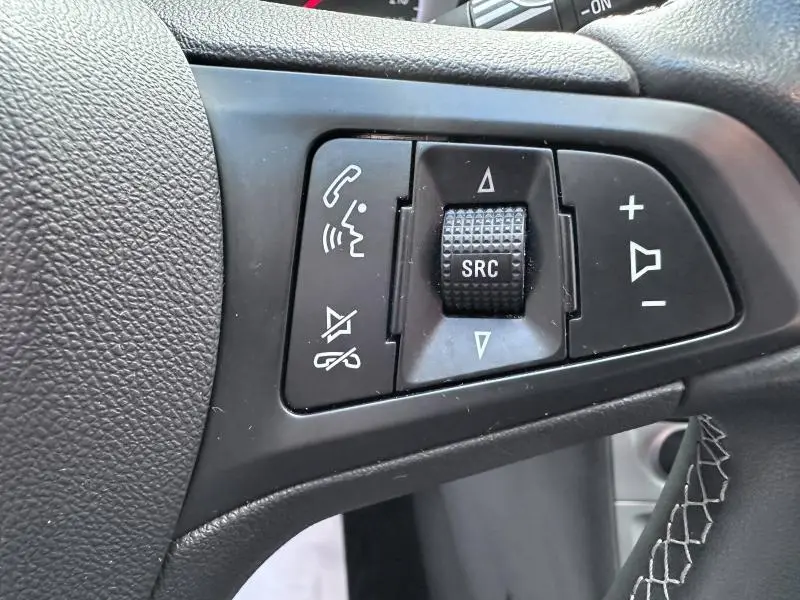 Gros plan sur les commandes vocales et volume au volant cuir noir de l'Opel Astra Sports Tourer gris cosmique 2021.