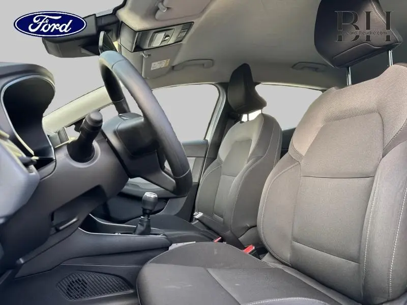 Vue intérieure côté conducteur de la Renault Clio blanche 2020, sièges tissu noir et volant réglable.