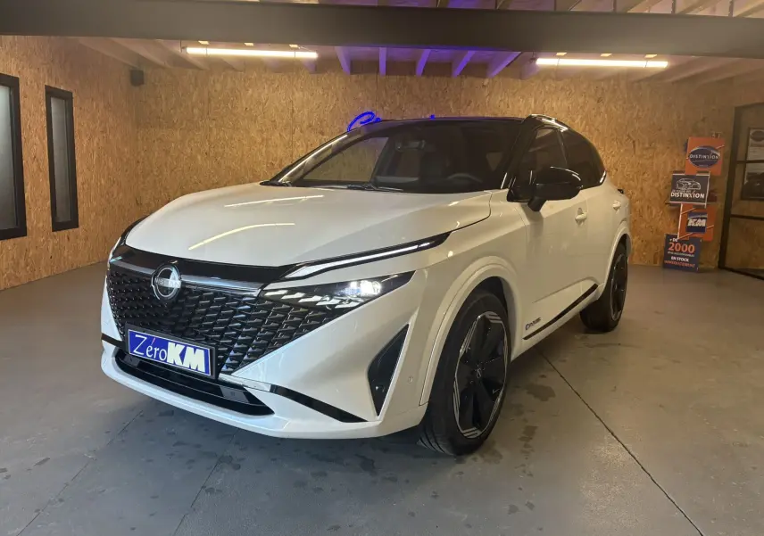 Nissan Qashqai blanc nacré avec toit noir, vue 3/4 avant droit, mettant en valeur sa calandre noire et ses phares LED fins.