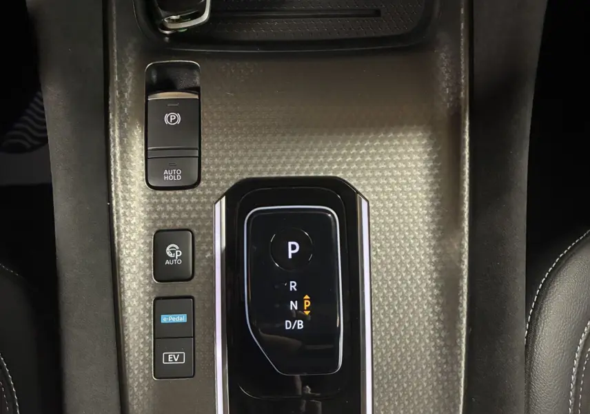 Vue plongeante sur la console centrale noire du Nissan Qashqai blanc nacré, avec levier de vitesses automatique et clé posée.