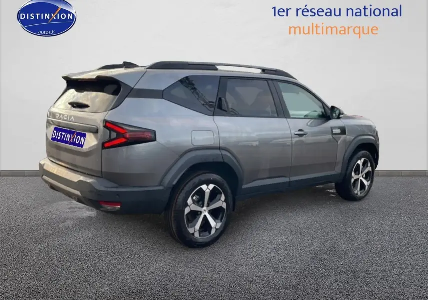 Vue 3/4 arrière droite du SUV Dacia Bigster gris schiste avec jantes alliage diamantées et barres de toit.
