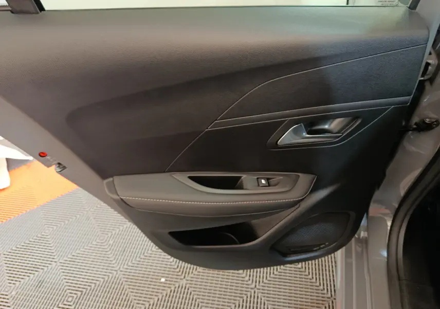 Vue rapprochée de la porte arrière droite gris foncé de la Peugeot 208 PureTech 100 S&S Allure avec commande de vitre et haut-parleur intégré.