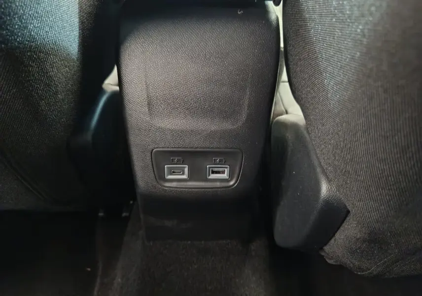 Prise USB type A et USB type C arrière sur console centrale noire du Peugeot 208 gris foncé, vue de dos des sièges.