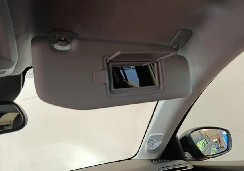 Vue intérieure du pare-soleil côté conducteur avec miroir intégré, rétroviseur et vitre latérale du Peugeot 208 gris foncé.
