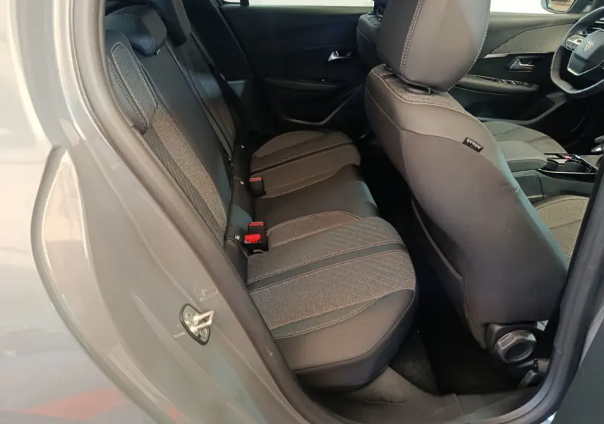 Vue intérieure côté arrière gauche de la Peugeot 208 gris foncé, montrant les sièges arrière en tissu et cuir.