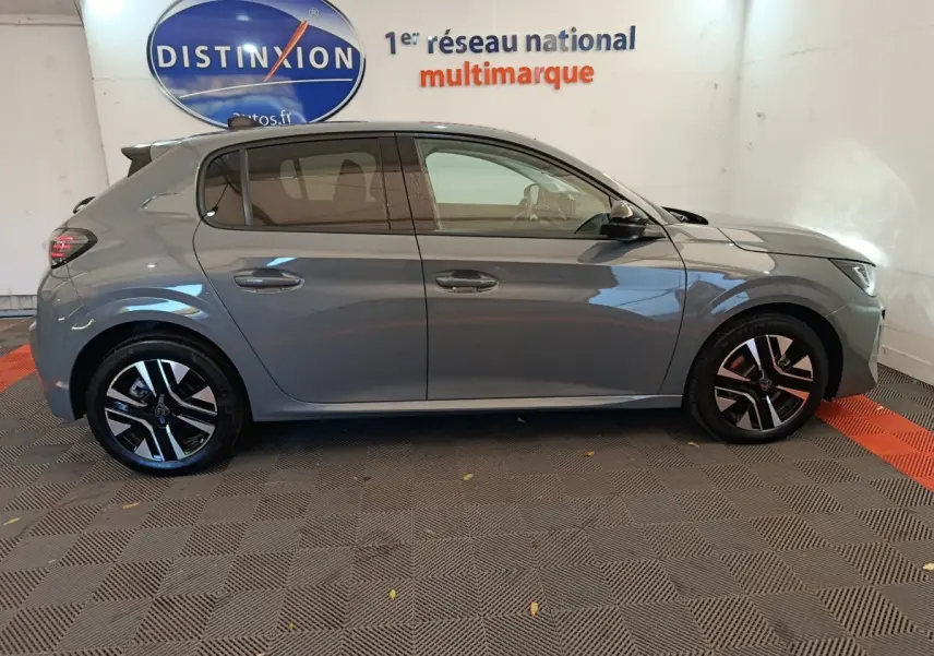 Profil côté gauche d'une Peugeot 208 gris foncé 2025 avec jantes noires et détails modernes visibles.