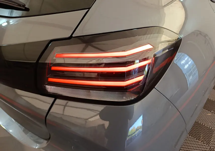 Gros plan sur le feu arrière droit allumé d'une Peugeot 208 PureTech 100 S&S Allure gris foncé 2025.